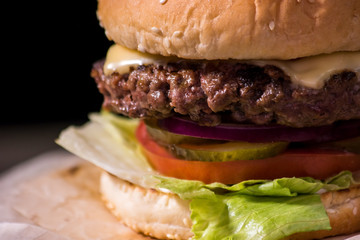 Hamburger close-up on black background. Fresh vegetables and grilled meat.