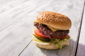 Burger on gray wooden background. Sesame bun, meat and vegetables.
