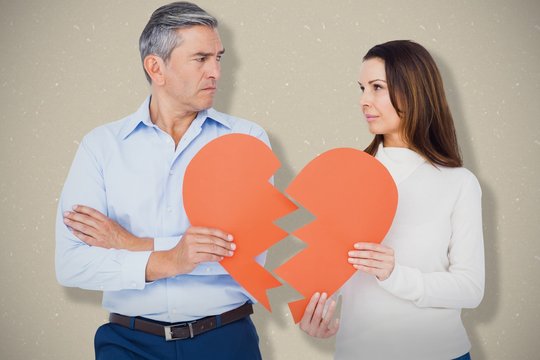 Composite image of couple holding broken heart shape paper