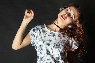 Cheerful girl with headphones listening to music and dancing.