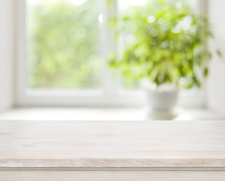Light wooden table on defocuced spring window background