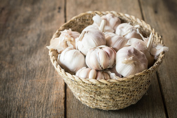 Garlic in a basket on an old wooden table.