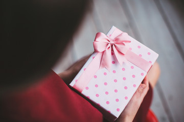 Gift with pink ribbon in female hands.