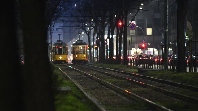 Tram che si incrociano di notte in viale di Milano con fermata e passaggio pedonale sul fondo luci e semafori della citt&agrave;