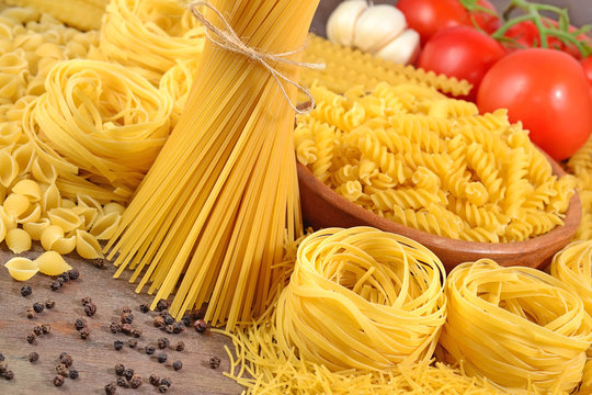 Uncooked Italian pasta, ripe tomatoes branch, garlic and black p