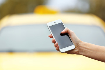 Woman ordering taxi by cellphone on blurred car background