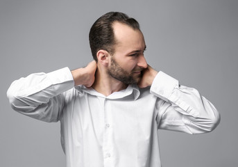Handsome man suffering from neck pain on color background
