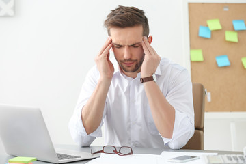 Handsome man suffering from headache in office