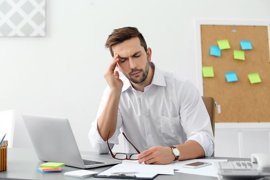 Handsome man suffering from headache in office