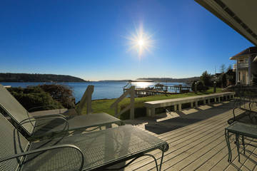 Large spacious deck of grey waterfront home at sunset - obrazy, fototapety, plakaty