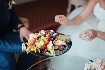 The bride and groom eat fruit dessert at the wedding