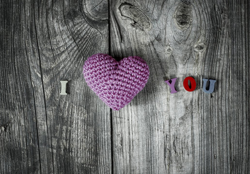 Knitted heart on gray wooden background