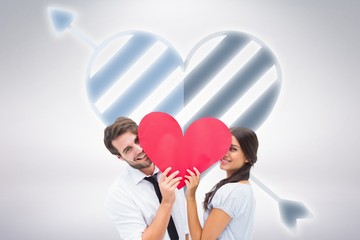 Composite image of couple smiling at camera holding a heart