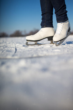 Young woman ice skating outdoors on a pond on a freezing winter