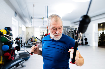 Fototapeta na wymiar Fit senior man in gym working out with weights.