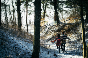 Couple holding hands run away to the forest in winter