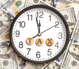 Clock with word "TAX" on dollars background. Time to taxes. Busi