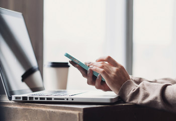Young beautiful woman using smartphone and laptop computer