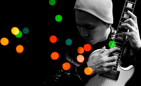 asian handsome musician playing electric guitar, isolated on black with colorful bokeh