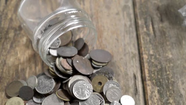 A glass jar with old coins on a wooden table
