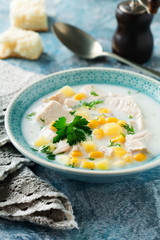 Homemade soup with chicken meat, corn, potatoes and parsley leaves in ceramic bowl. Simple stew. Selective focus.