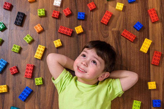 Little caucasian child playing with lots of colorful plastic blo