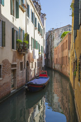 Fototapeta na wymiar Boat anchored on canal near house in domestic part of traditional Venice