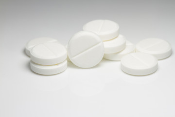 White medical pills on white background with shadows and soft light