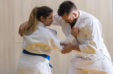 Photo sur Plexiglas Arts martiaux Woman and man judo fighters in sport hall