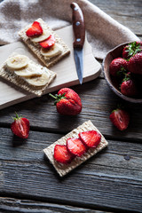 Fruity toast on wooden background. Strawberries, bread, butter and cheese.Vintage style