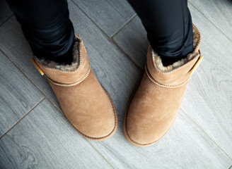 Girl in brown ugg boots in leather pants. Fashion, style, modern. Grey wood floor