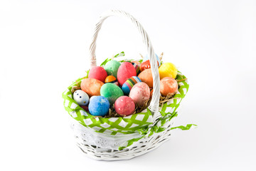 Colored easter eggs in a basket isolated on white background
