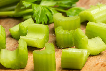 Apio cortado en trozos sobre una tabla de madera. Vista en primer plano y de frente