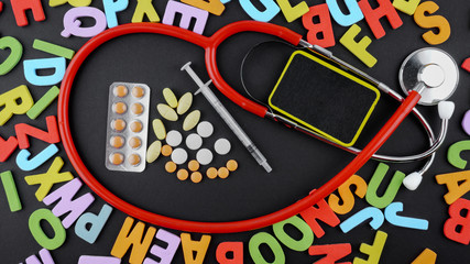 Stethoscope with medicine and syringe on blackboard