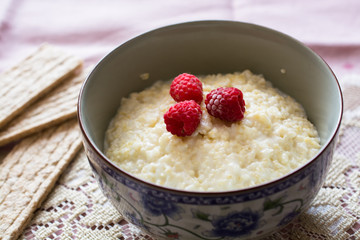 Nice bowl of milk porridge with raspberries.
