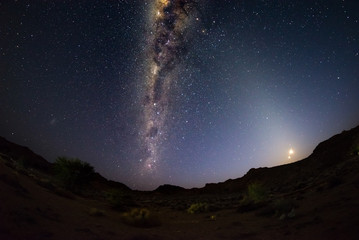 Starry sky and Milky Way arc, outstandingly bright, with rising moon, captured from the Namib...