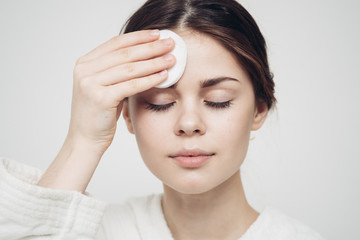 Fototapeta premium woman wipes her forehead with a cotton disc, closed eyes