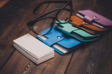 notebooks of different colors, paper, wooden background, glasses