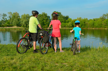 Fototapeta premium Family on bikes outdoors, active parents and kid cycling and relaxing near beautiful river, fitness concept 