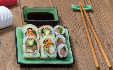 Sushi Set rolls with salmon served on green plate on wooden table