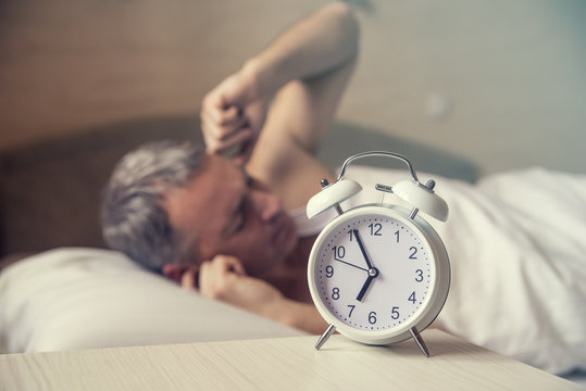 sleeping man disturbed by alarm clock early morning. Angry man 