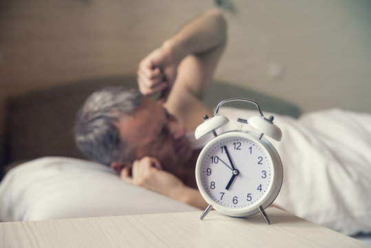 sleeping man disturbed by alarm clock early morning. Angry man 