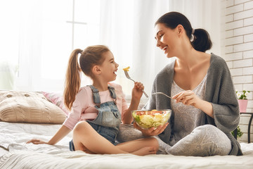Obraz na płótnie Canvas Mother and daughter eating salad