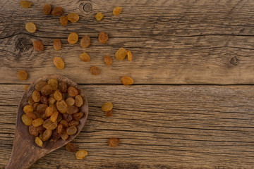 Raisins in wooden spoon on old wooden table.