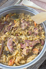 Sauerkraut with smoked pork meat in pot on table