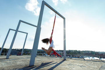 Beautiful aerial dancer, silk dance on roof at sunrise