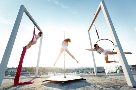 Athletic dancers performing aerial & pole dance on rooftop