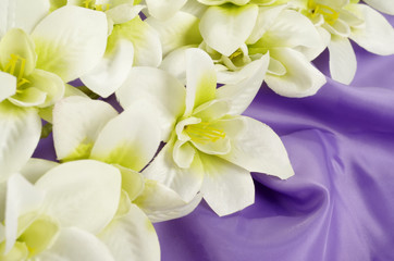 Artificial flowers for design and home decoration - lily on textile lilac background