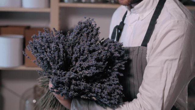 happy smiling florist man making bunch at flower shop. people, business, sale and floristry concept. Bouquet with lavender