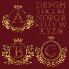 Vintage monogram kit. Golden patterned letters and floral coat of arms frames for creating initial logo in antique style.